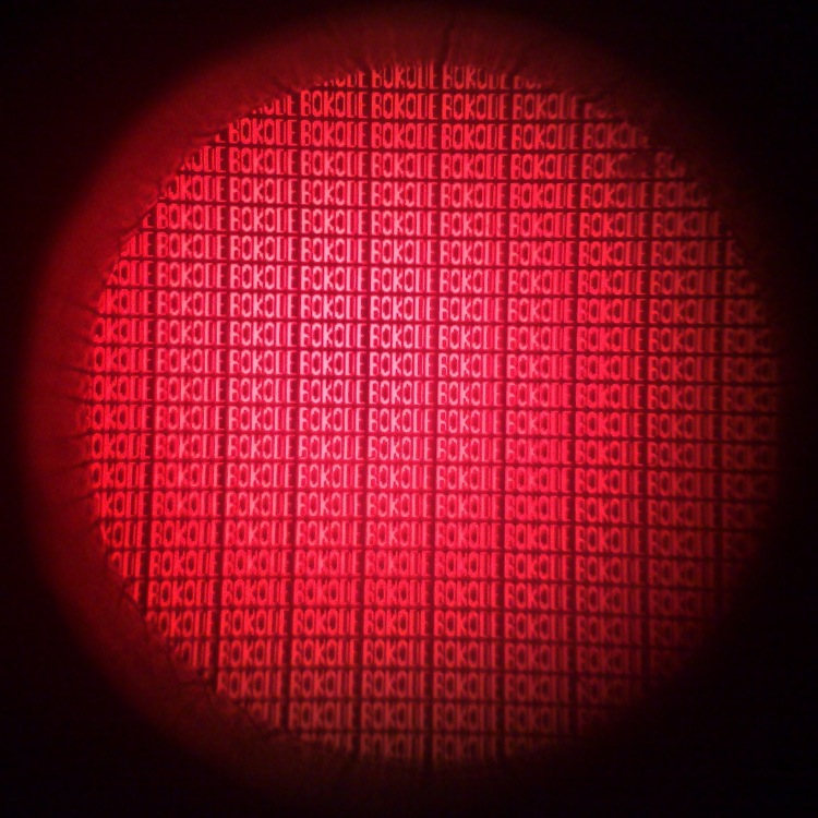 The unit of the Bokode. A Bokode is composed of a tiny optical lens which hides a series of miniaturized 2D barcodes. Surprisingly, a camera taking an out-of-focus picture is able to create a sharp image of the Bokode.